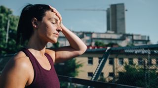 Woman in activewear wiping sweat off her forehead after being out for a run outdoors