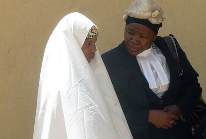 Wasila Tasiu speaks with an unidentified defence counsel outside the courtroom
