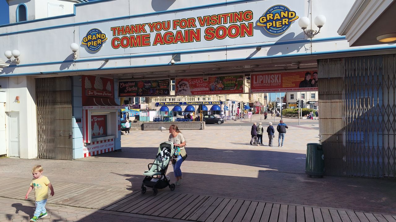The entrance to the Grand Pier is visible, with a sign that says "Thank You for Visiting Come Again Soon" and people walking in and out.