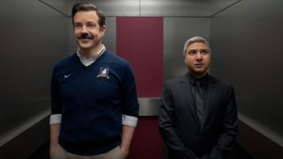 From left to right: Jason Sudeikis and Nick Mohammed standing in an elevator.