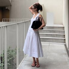 Eliza Huber wearing an all white outfit and black bag.