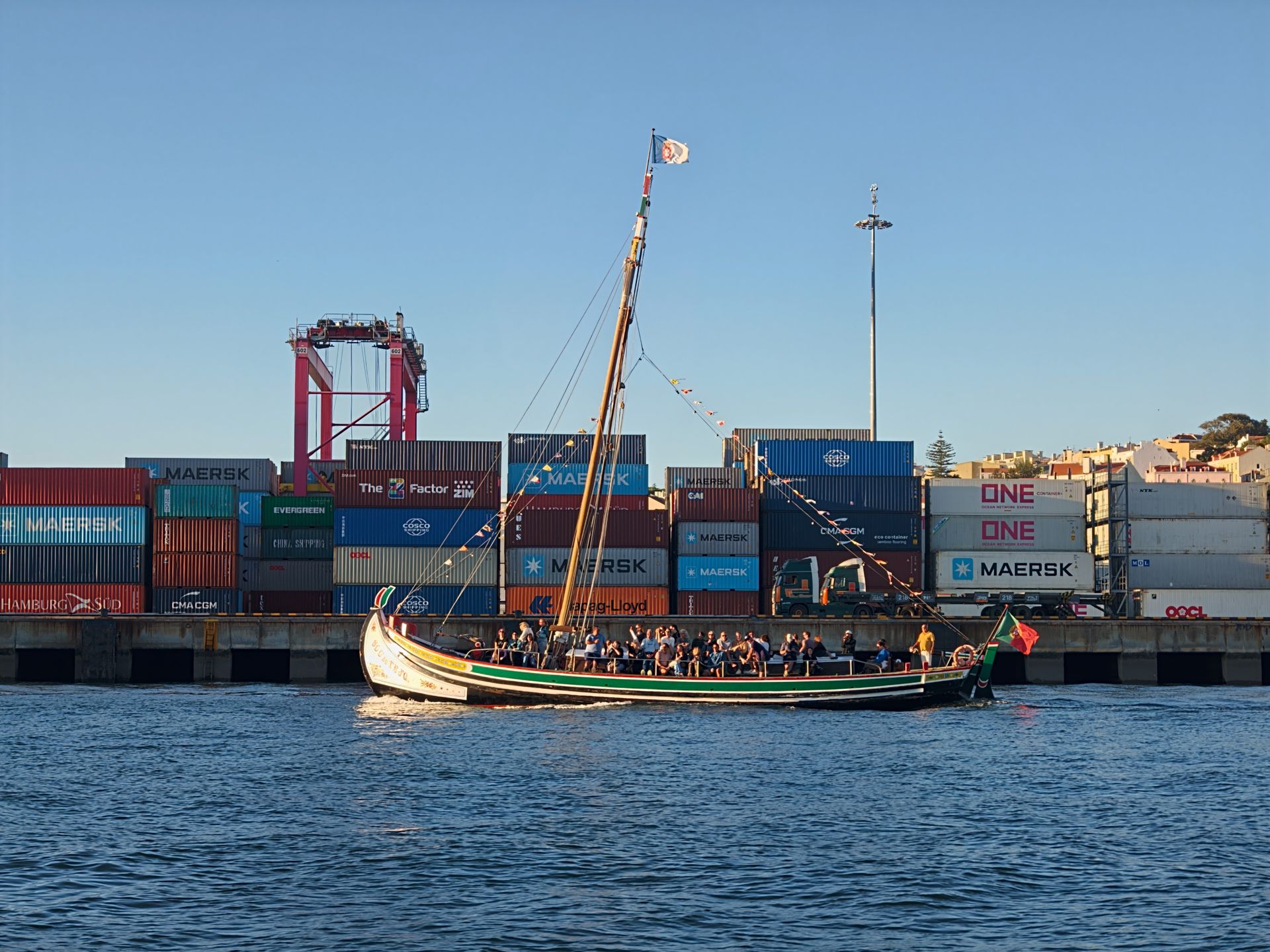  boat on the water, infront of containers on land