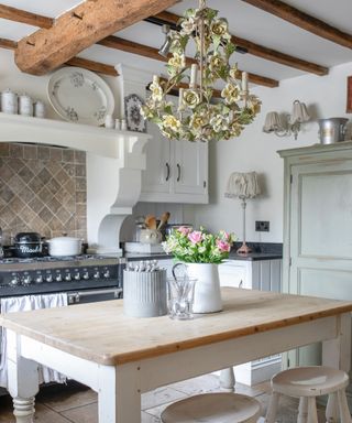 vintage style kitchen with ornate chandelier, farmhouse table and white units