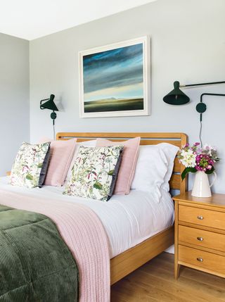 bedhead with pink and green bedlinen and painting above bedhead