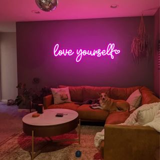 A neon pink wall light affixed to a living room wall.