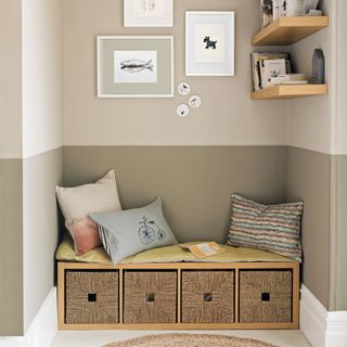 A dining room with a light grey and dark grey wall, floating shelves and a storage unit with baskets as a bench seat in an alcove