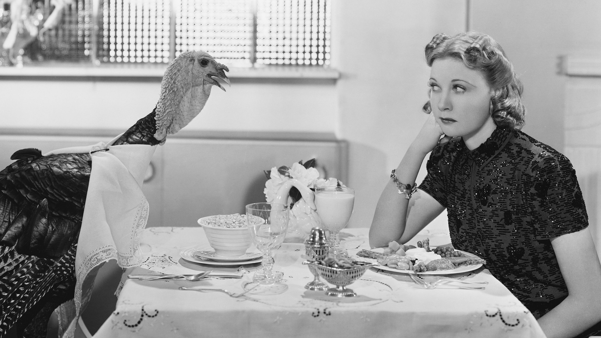 Woman eating meal at table with live turkey