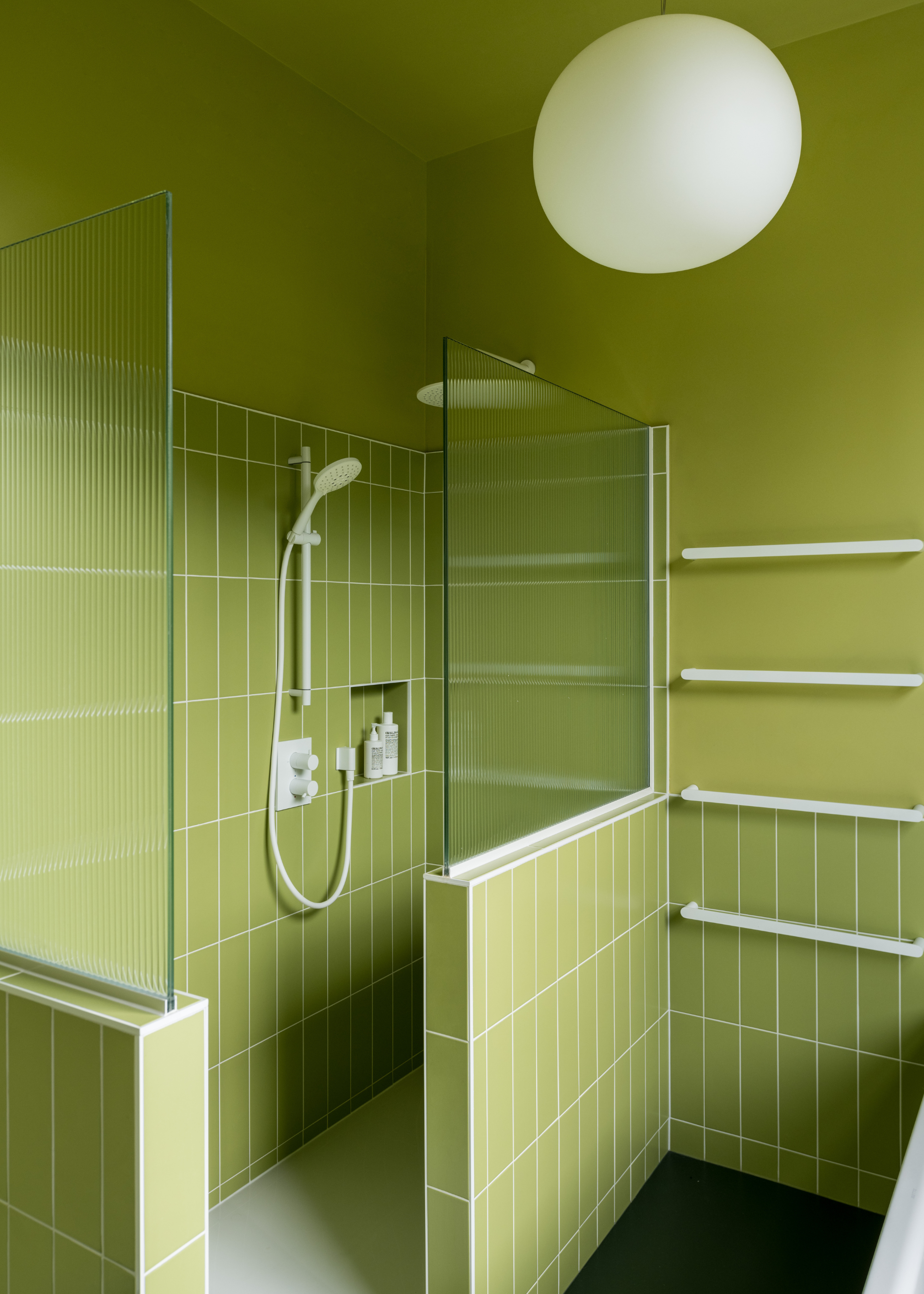 A lime green bathroom with colo-drenched tiles and white grout, fixtures and lighting