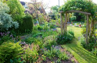 Grass path through arch in garden