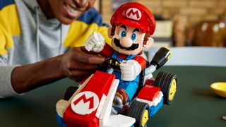 Lego Mario & Standard Kart being held by a person sat at a table