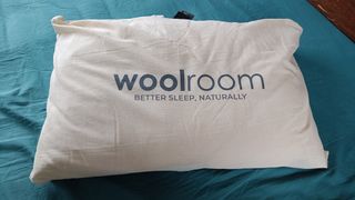 Woolroom Deluxe Washable Wool Pillow on test on a bed with a teal sheet