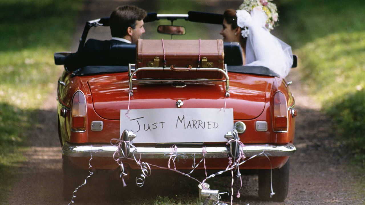 picture of a bride and groom driving away in a car with a &amp;quot;just married&amp;quot; sign on the back