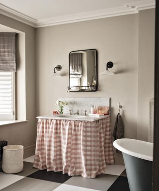 neutral bathroom with beige walls, large checked flooring and pink gingham fabric skirt underneath sink