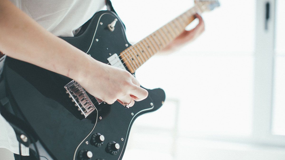 Close up of woman&#039;s hands playing electric guitar