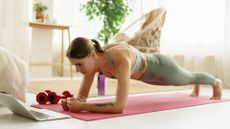 woman holds low plank on yoga mat