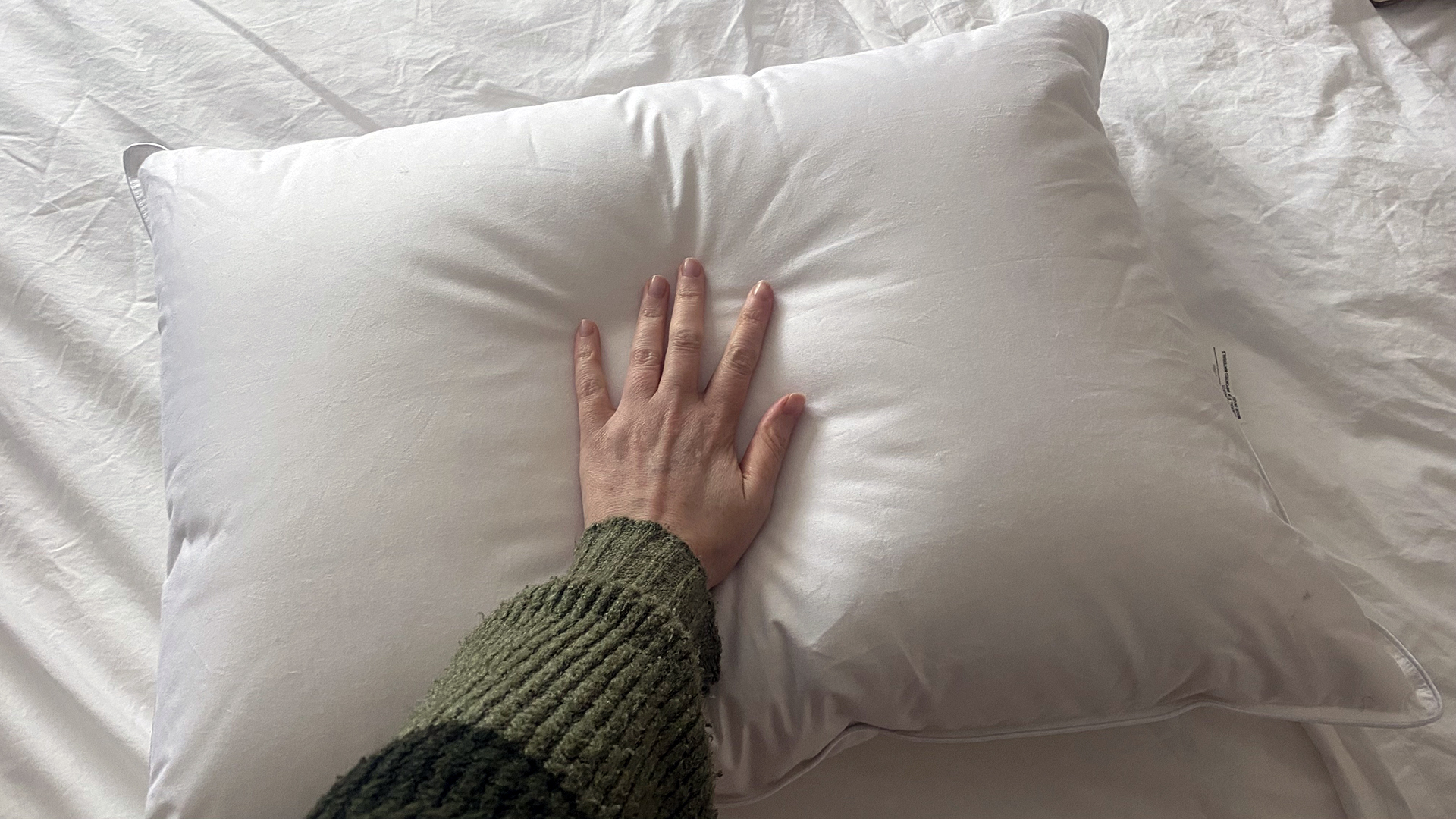 A hand touches the surface of the Downright Mackenza WD pillow, feeling if the surface is soft and cool to the touch