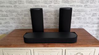 The Sony Bravia Theatre Trio sits on a wooden sideboard in front of a white brick wall.