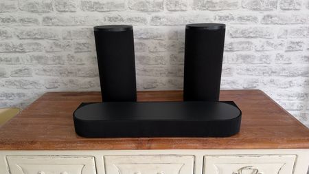 The Sony Bravia Theatre Trio sits on a wooden sideboard in front of a white brick wall.