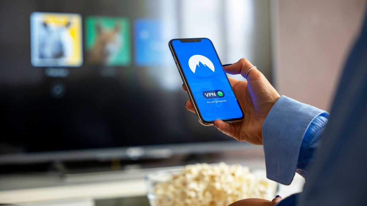 A person sat in front of a TV with a VPN connected in the foreground. In the background Netflix is on the TV