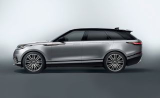 The side view of a Grey Range Rover Velar photographed in against a grey background
