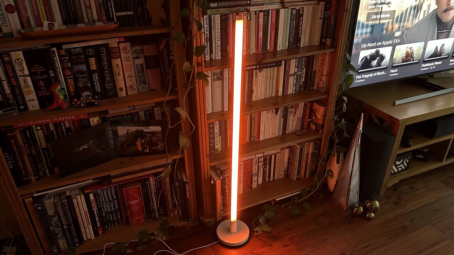 Wiz Luminaire Pole Floor Light glowing orange in a corner of the living room.
