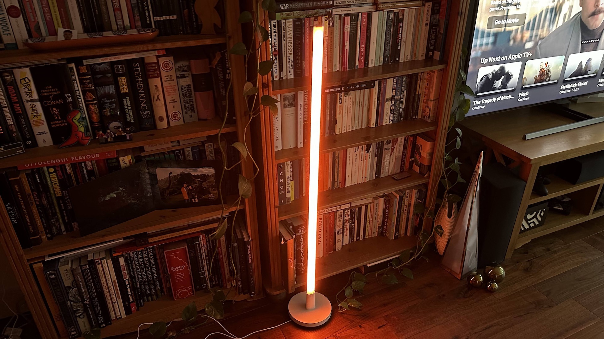 Wiz Luminaire Pole Floor Light glowing orange in a living room corner.