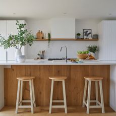 Kitchen with white cabinets, island with sink and wooden panneling