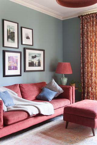 room with green walls and deep pink sofa framed pictures behind