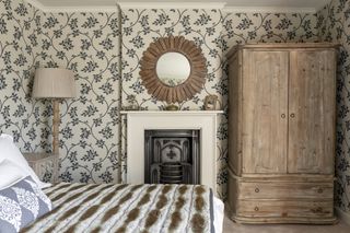 A bedroom with wall-to-wall wallpaper, punctuated by a mirror