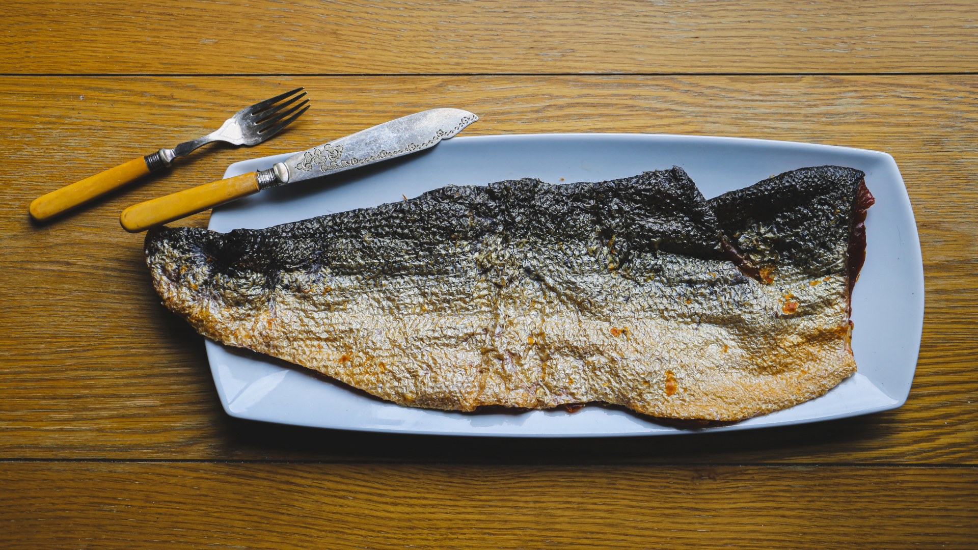 Salmon fish skin on a plate with a knife and fork