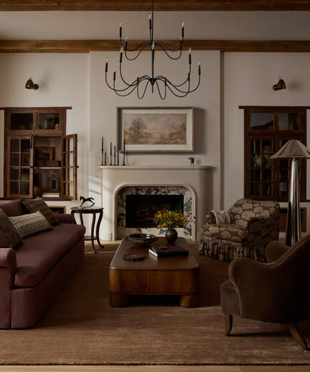 a heritage-inspired living room with dark wood furniture, a plum couch, and an iron chandelier 