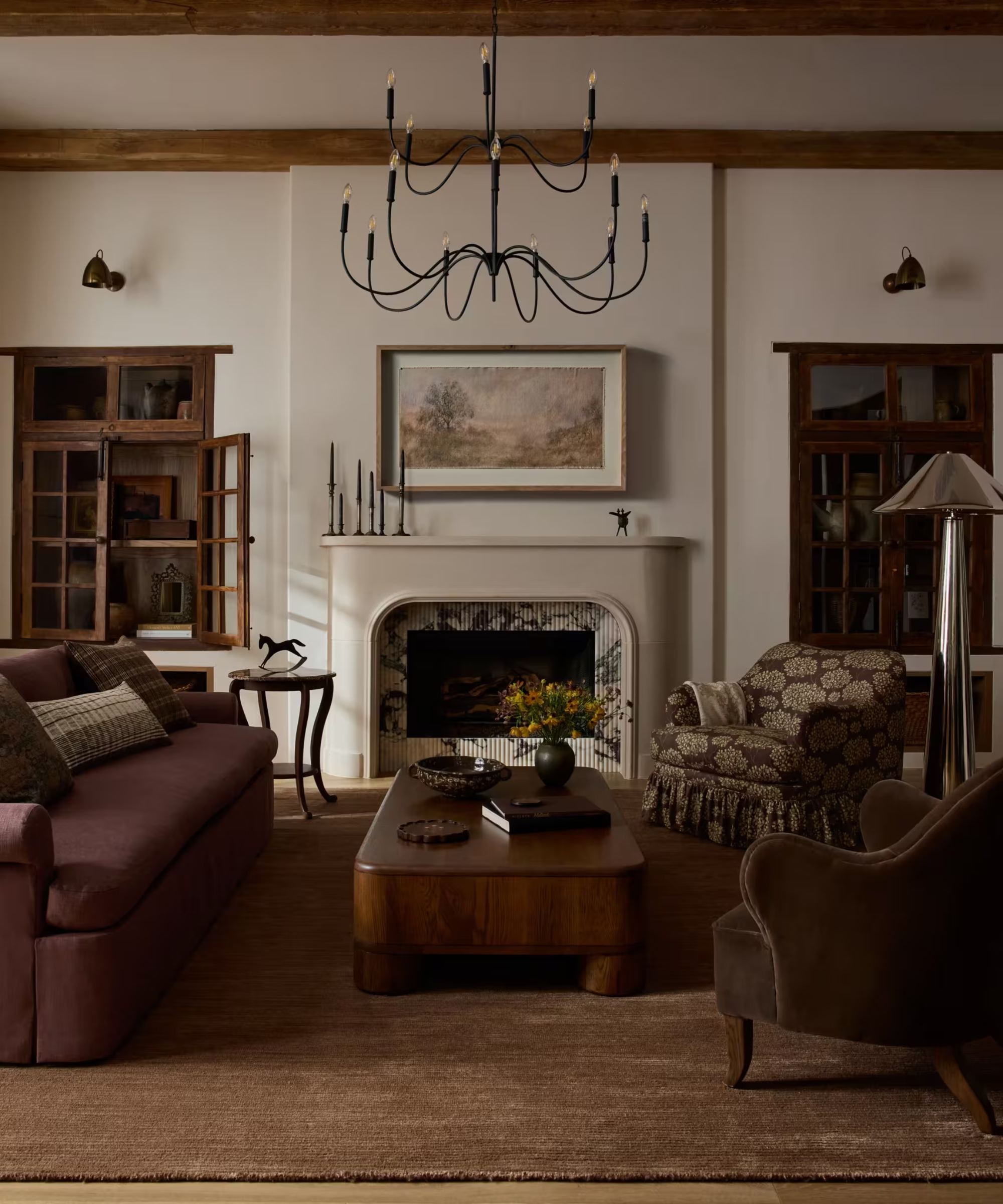 a heritage-inspired living room with dark wood furniture, a plum couch, and an iron chandelier