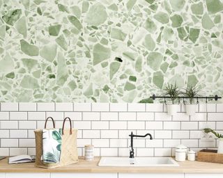 Modern kitchen with white metro tiles and terrazzo effect green feature wallpaper