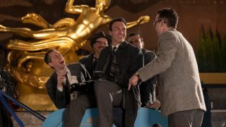 Reid Scott as Gordon Ford sitting on a cart surrounded by the writers in The Marvelous Mrs. Masiel