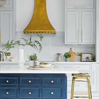 grey kitchen with navy blue island and gold extractor hood