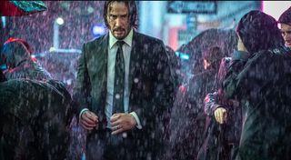 Keanu Reeves as John Wick walking through the rain without an umbrella