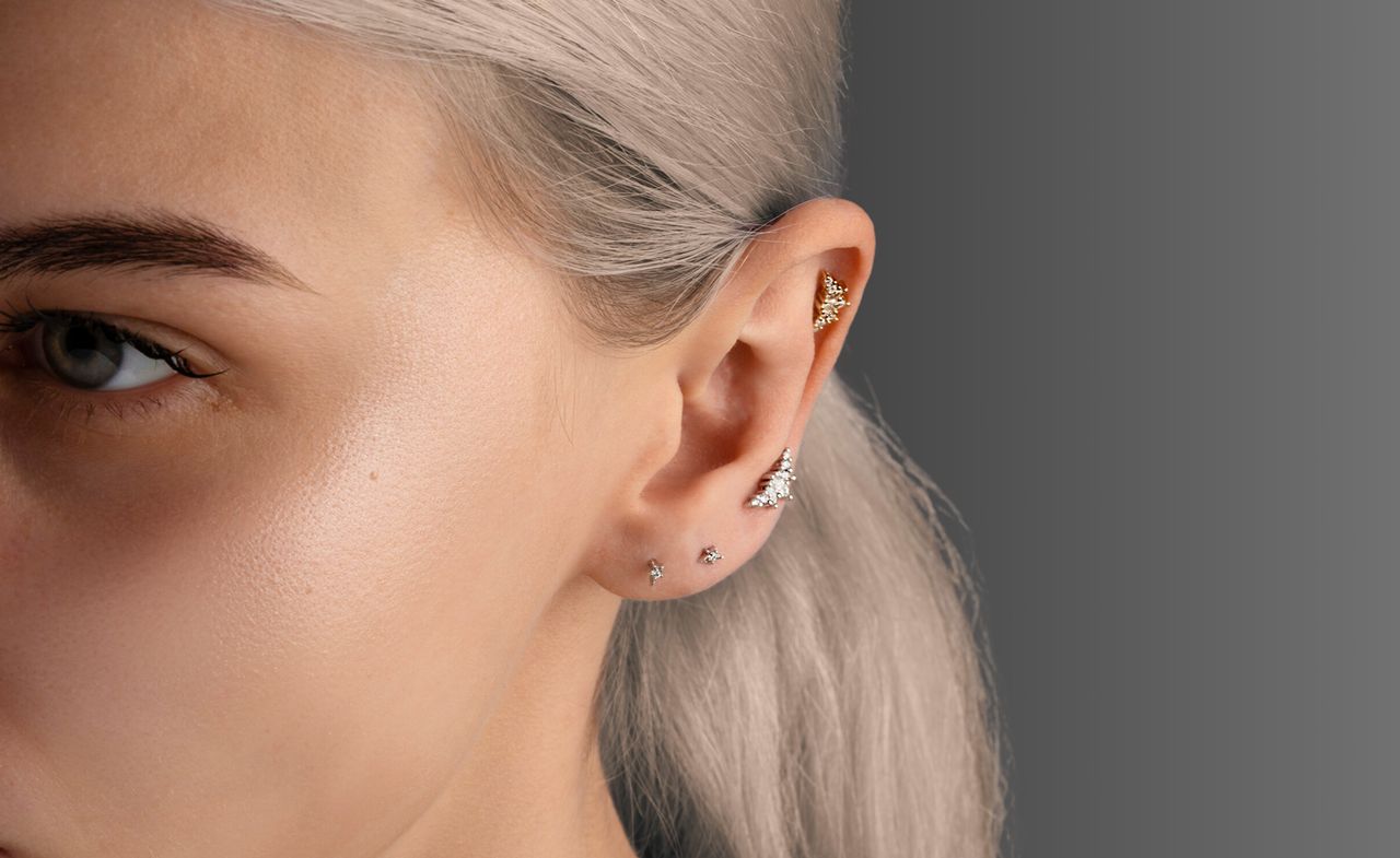 illustrating piercing tips, side of woman&#039;s face with multiple earrings in ear