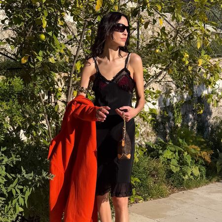 Alexa Chung wearing a red trench with a black slip dress, Louis Vuitton bag, and leopard-print Alaia thong high-heel sandals in France