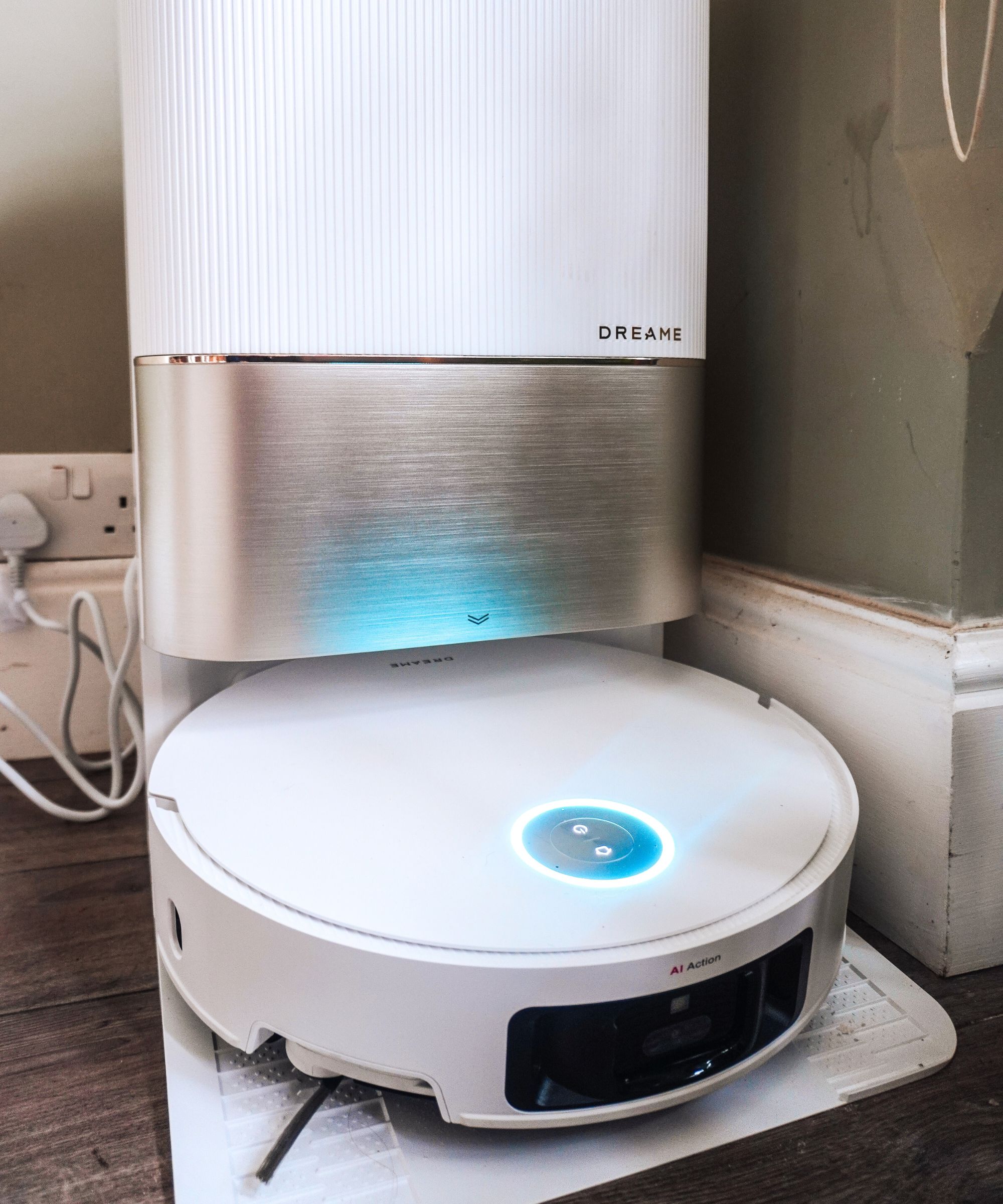 A Dreame X50 Ultra robot vacuum in a white and silver base station, with a green wall behind it