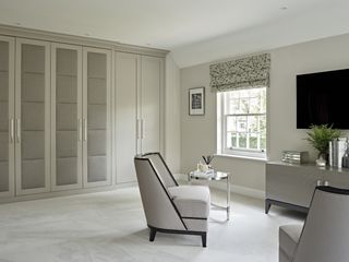 fitted bedroom wardrobes in neutral room scheme with seating area and TV