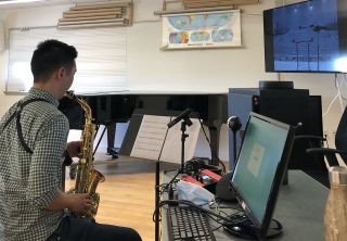 Saxophone performer working in a classroom space at San Francisco Conservatory of Music, featuring Focusrite RedNet X2P 2x2 Dante audio interface