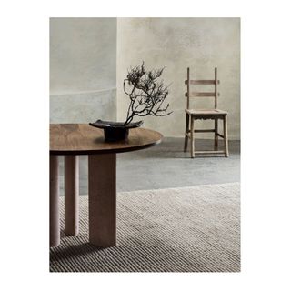 round wood table and neutral color rug on grey floor