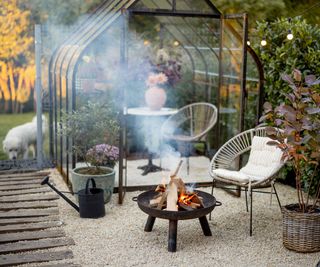 A fire pit next to a stylish greenhouse