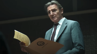 Liam Neeson opening a file in an interrogation room in The Naked Gun 2025