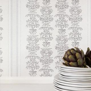 A black-and-white patterned wallpaper, with a stack of white plates and an artichoke in front