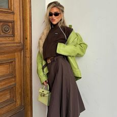 woman in dark brown outfit and lime green coat