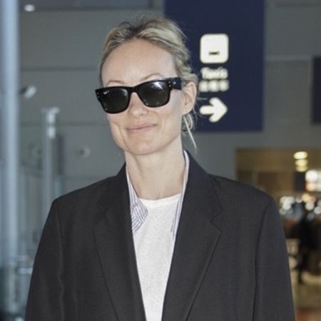 Olivia wears a blazer with a white tee and black sunglasses.