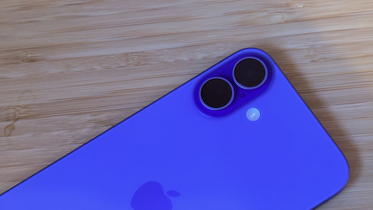 An ultramarine blue iPhone 16 on a wooden desk
