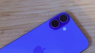 An ultramarine blue iPhone 16 on a wooden desk