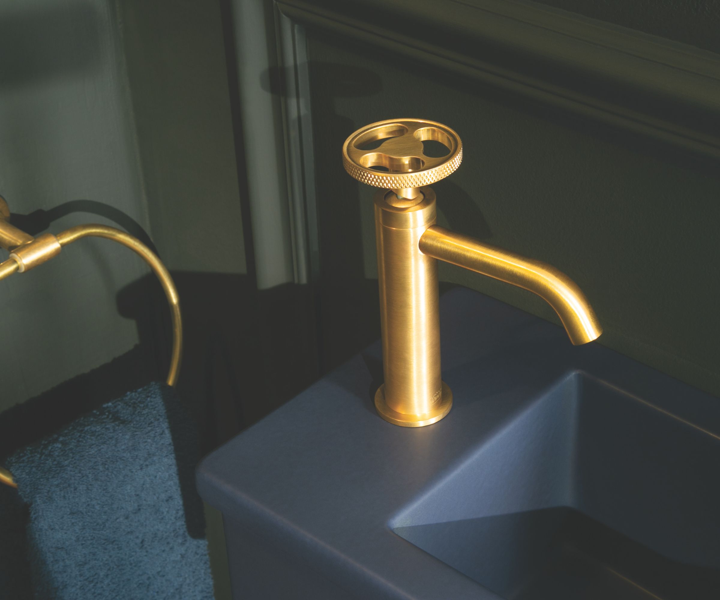 Brushed brass mono basin tap on a dark blue vanity with matching brass towel rail.